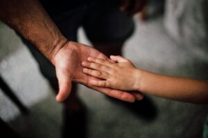 Manos de una persona adulta y una niña unidas